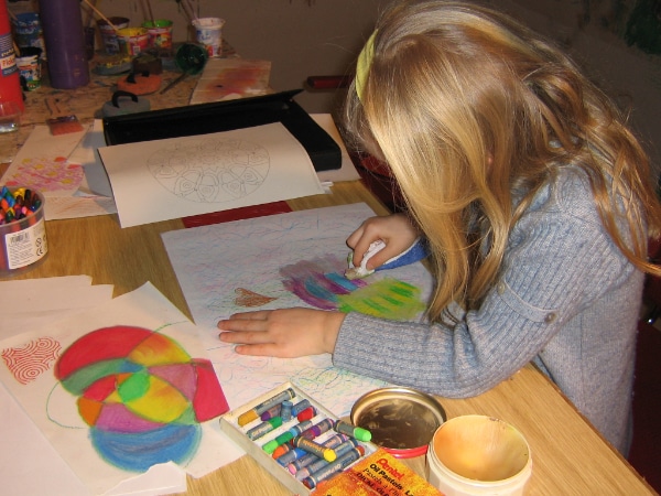 Kind gestaltet in einer Kreativwerkstatt ein Bild mit Farben