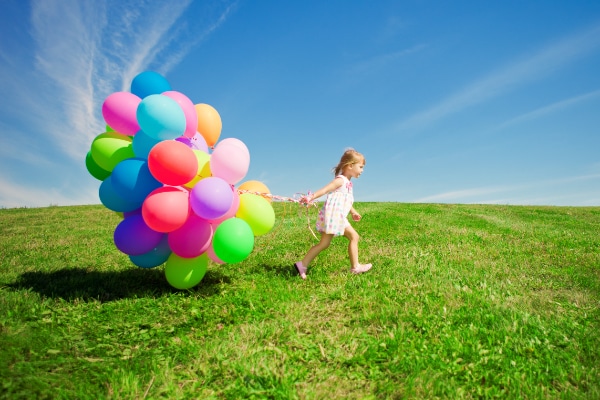 Kind mit Luftballons auf einer Wiese