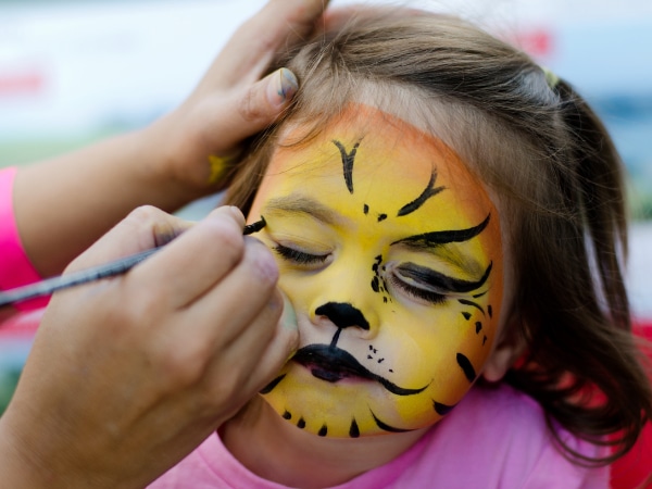 Kinderschminken - Ein Kind wird als kleiner Tiger geschminkt