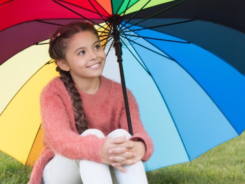 Fröhliches Mädchen unter einem bunten Schirm